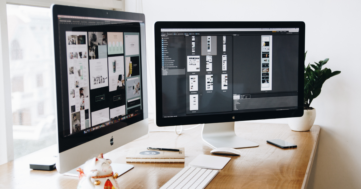 Dois monitores exibindo um software de design com várias telas de site sendo montadas