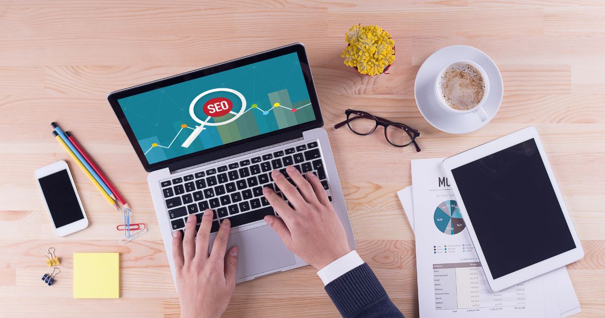 Pessoa analisando em um notebook um gráfico de desempenho com o ícone de lupa de SEO na tela