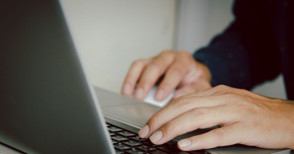 Close das mãos de uma pessoa digitando no teclado de um notebook