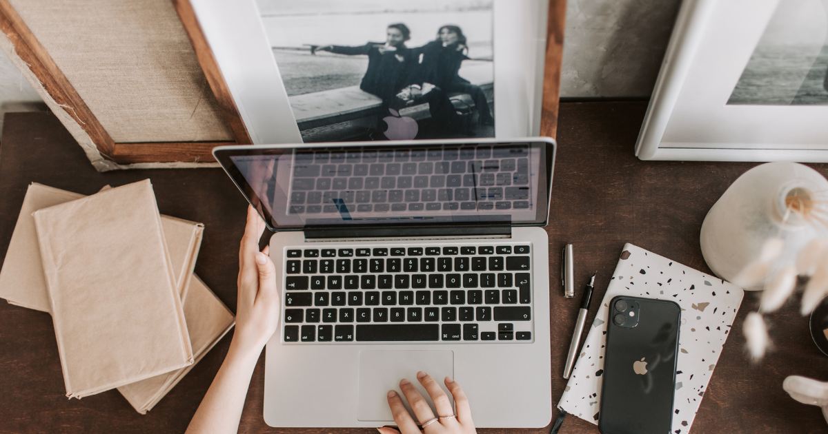 Mesa de trabalho vista de cima com notebook, celular e cadernos, em um ambiente de planejamento